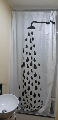 a white shower curtain with a black and white pattern at Fig Tree Cottage in Greytown