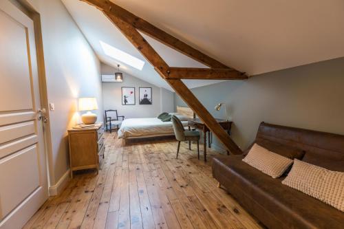 een zolderkamer met een bank en een bed bij La maison d'à côté in Mont-de-Marsan