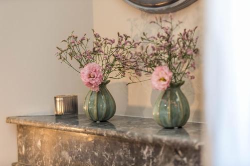 two green vases with pink flowers on a table at La maison d'à côté in Mont-de-Marsan