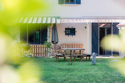 a house with a bench and an umbrella in the yard at La maison d'à côté in Mont-de-Marsan
