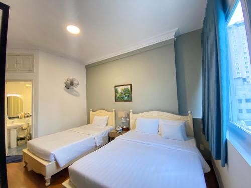 two beds in a small room with a window at A25 Hotel - 35 Mạc Thị Bưởi in Ho Chi Minh City