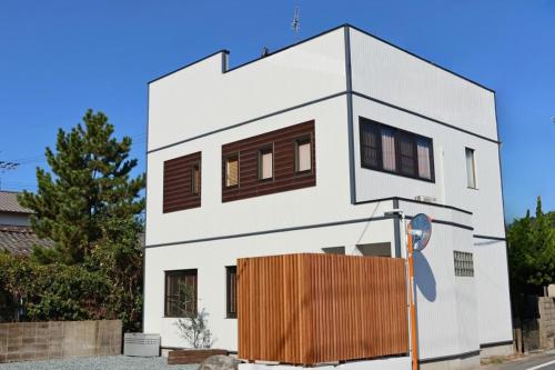 a white house with brown windows on a street at ロハスResort宮浦 in Fukuoka