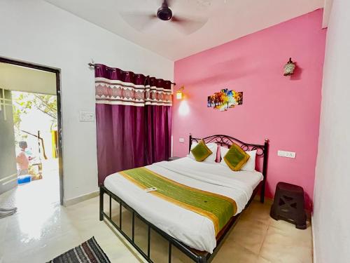 - une chambre avec un mur rose et un lit dans l'établissement Dipty Welcome Stay, à Vagator