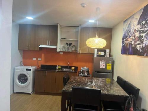 uma cozinha com uma mesa e uma máquina de lavar roupa em Chic and Cozy 1-Bedroom Condo em Cagayan de Oro