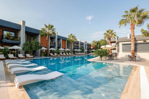 a pool at a resort with lounge chairs and palm trees at Forest In Hotel in Kemer