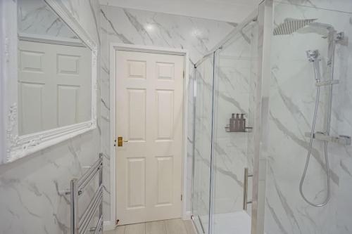 een witte badkamer met een douche en een witte deur bij Coastal Views Apartment Cleethorpes in Cleethorpes