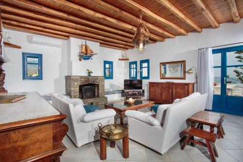 a living room with white chairs and a fireplace at Martineli Residence - A Beachfront Estate in Drios
