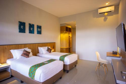 a hotel room with two beds and a television at Grand Harvest Resort & Villas in Banyuwangi