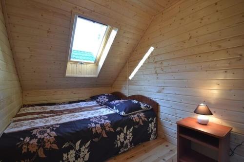 een slaapkamer met een bed in een houten hut bij Year round holiday house with a terrace near the sea Pustkowo in Pustkowo
