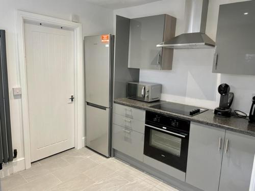 a kitchen with a stove and a refrigerator at Modernised Cottage in the Heart of Sketty in Swansea