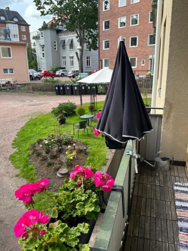 an umbrella sitting on a fence next to pink flowers at Pråmkanalens Pensionat i Karlstad in Karlstad