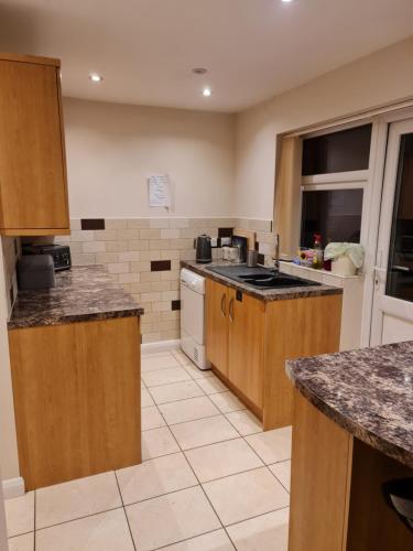 a large kitchen with wooden cabinets and appliances at Double Room near Airport in Takeley