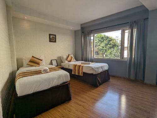 2 camas en una habitación con ventana en Nyadha House Bed & Breakfast, en Pātan