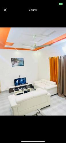een woonkamer met twee witte banken en een tv bij Charly-Calavi Appartement in Ouékè-Zoumè
