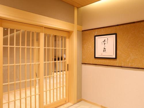 a room with a glass door and a wall with a picture at Beppu Hatto Onyado Nono Beppu in Beppu