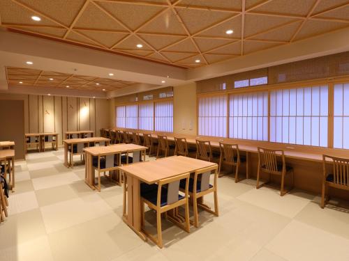 a dining room with tables and chairs and windows at Beppu Hatto Onyado Nono Beppu in Beppu