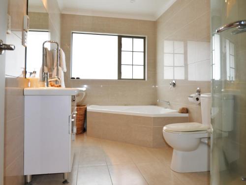 a bathroom with a tub and a toilet and a sink at Tauranga Homestead Retreat in Tauranga