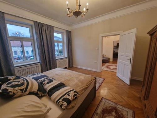 1 dormitorio con 1 cama, 2 ventanas y lámpara de araña en City Loft Stegersbach, en Stegersbach