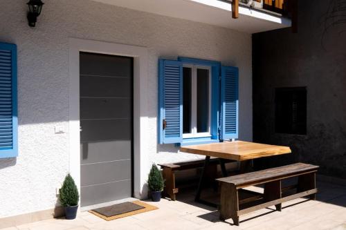 a table and bench in front of a house with blue shutters at 'Piccolo Paradiso' in Angera