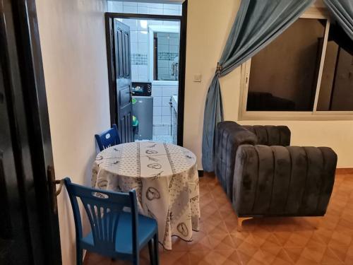 a living room with a table and chairs and a couch at Charmant,bien localisé et lumineux Appartement F2M/401A in Douala