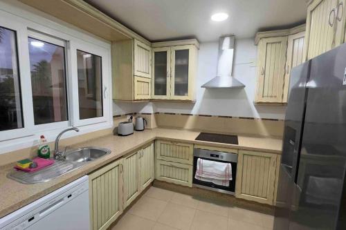 una cucina con mobili in legno e un frigorifero in acciaio inossidabile di Chalet Adosado Cerca Gibraltar a Alcaidesa