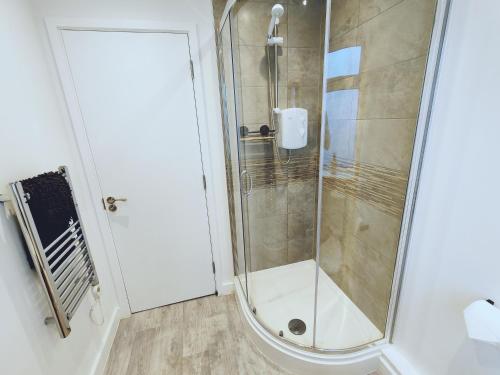 a shower with a glass door in a bathroom at Beautiful Stylish Loft Apartment Perfect Summer Getaway Christchurch Centre in Christchurch