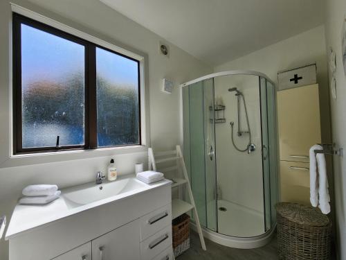 a bathroom with a sink and a glass shower at Hahei Ocean's 76 in Hahei