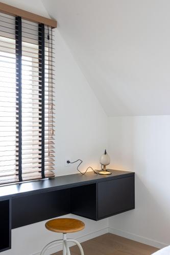 a desk with a lamp and a stool in a room at stek&stoof in Sint-Pauwels