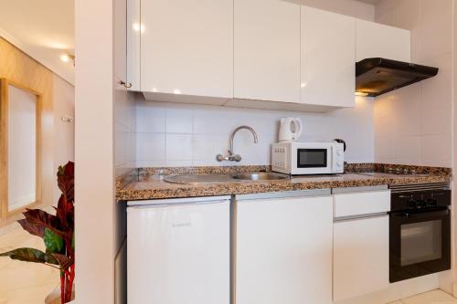 een witte keuken met een wastafel en een magnetron bij Beautiful, quiet apartment with heated pool AP236 in San Miguel de Abona