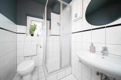 uma casa de banho branca com um WC e um lavatório em Favorite Stays - Suite and More - Westfeld em Neuss