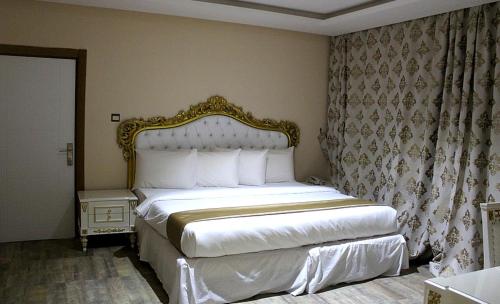 1 dormitorio con 1 cama blanca con marco dorado en Ellyxville Hotel en Lekki
