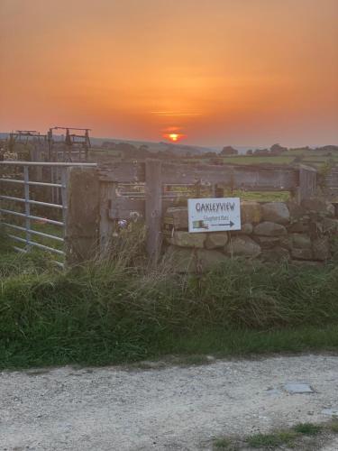 um sinal numa cerca com um pôr-do-sol ao fundo em Oakley View Shepherds Hut with hot tub em Whitby