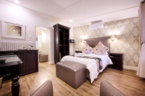 a large bedroom with a large bed and a desk at Postmasburg d Olive Rose Boutique Hotel in Postmasburg