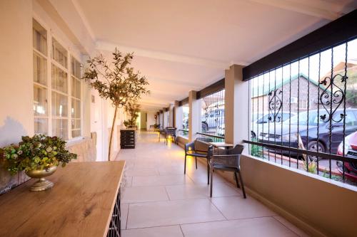 a hallway with tables and chairs and windows at Postmasburg d Olive Rose Boutique Hotel in Postmasburg