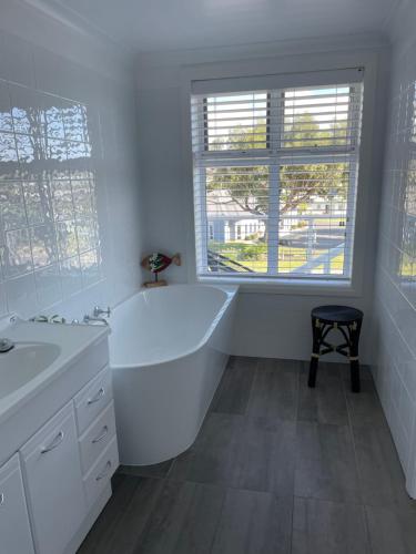 a white bathroom with a tub and a window at Church Street Villas in Stanley