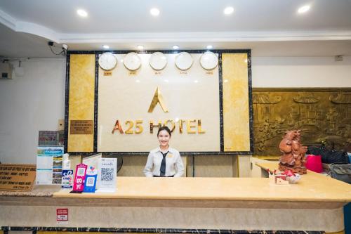 a man standing behind a table in front of a hotel at A25 Hotel - 35 Mạc Thị Bưởi in Ho Chi Minh City