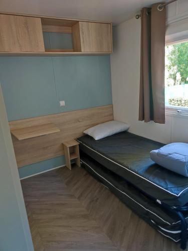 une petite pièce avec un lit et une fenêtre dans l'établissement superbe mobil home 6/8 pers,clim, sans vis a vis dans camping 4* espace aquatique, à Vias