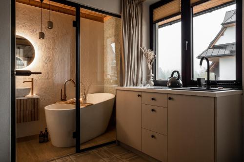 een badkamer met een ligbad en een wastafel bij ApartSki 18d in Zakopane
