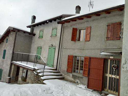 a building with green and red doors in the snow at Terratetto 90 mtq 10 posti letto in SantʼAnna Pelago