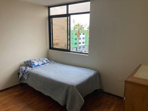 Apartamento en Pueblo Libre في ليما: غرفة نوم صغيرة بها سرير ونافذة