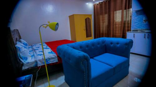 ein Wohnzimmer mit einem blauen Sofa und einem Bett in der Unterkunft Prince Studio at Twiga House in Kigali