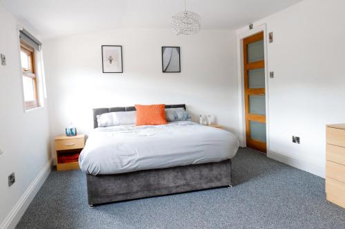 a bedroom with a bed with white sheets and orange pillows at Stunning Lodge with Hot Tub on Private Lake in Harrogate