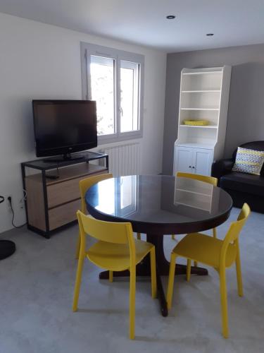 a living room with a table and yellow chairs at Appartement double in Mende