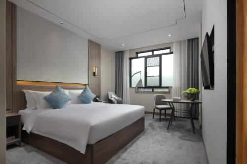 Un dormitorio con una gran cama blanca y una mesa en NATIONAL SCENIC SPOT SUNSHINE RESORT HOTEL, en Zhangjiajie