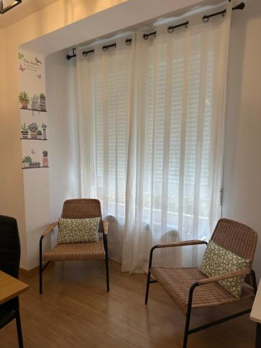 two chairs in front of a window with curtains at LA ISLA DE PEREZ GALDOS in Logroño