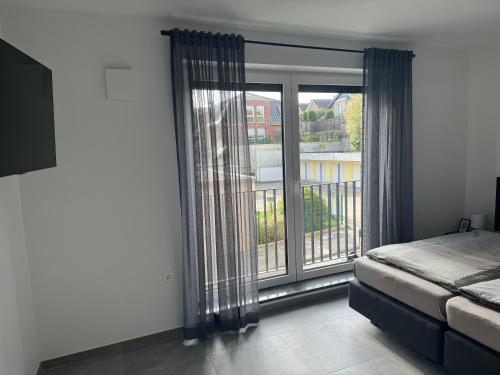 a bedroom with a bed and a large window at Rathausplatz Residenz in Übach-Palenberg