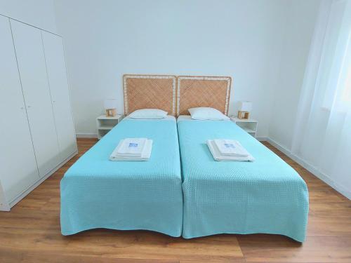 a bed with blue sheets and two towels on it at A Casa dos Azulejos in Santiago do Cacém