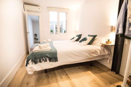 a bedroom with a large white bed with green pillows at Capricho de la Judería Suites in Córdoba