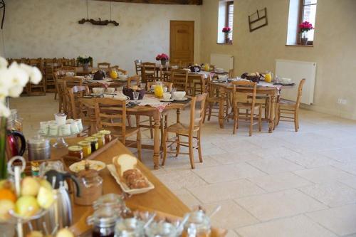 Habitación grande con mesas y sillas con comida. en La Grange de Boulaines, en Méru