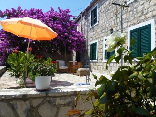 an orange umbrella sitting next to a building with purple flowers at Apartment Vanja in Bol
